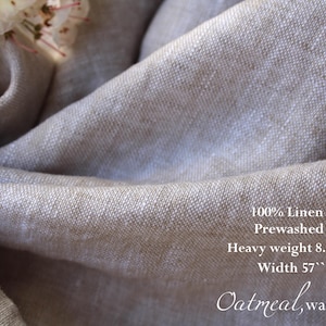 K&ouml;nnte beinhalten: Nahaufnahme eines gefalteten, hellbeigen Leinenstoffs. Der Stoff ist vorgewaschen und hat ein schweres Gewicht von 229 Gramm. Die Breite betr&auml;gt 145 cm. Der Text auf dem Stoff lautet "100% Linen", "Prewashed", "Heavy weight 8.1oz", "Width 57"" und "Oatmeal, washed".