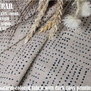 May include: A natural-colored fabric featuring a dark navy blue dotted pattern. The text on the fabric reads: INK TRAIL, 55% linen, 45% cotton, Lightweight, 4.3oz/145gsm, Width 55". The material is draped and includes decorative dried wheat stalks.
