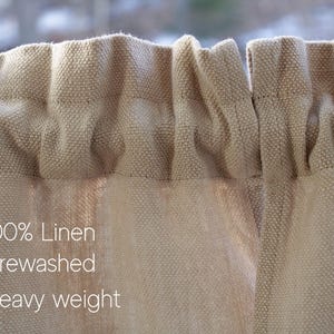 May include: Close-up of a beige linen curtain with a textured weave. The curtain is pre-washed and heavy weight. The text "100% Linen", "Prewashed", and "Heavy weight" is printed on the curtain.