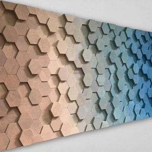 Puede incluir: Una pieza de arte de pared hecha de madera con un degradado de colores de marrón claro a azul. La madera está dispuesta en un patrón de panal.