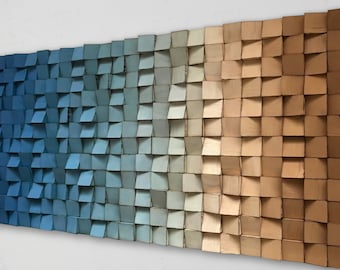 Op de afbeelding: Een wandkunstwerk gemaakt van hout met een gradiënt van blauwe, grijze en bruine kleuren. Het hout is in een verspringend patroon gerangschikt, waardoor een textuur ontstaat.