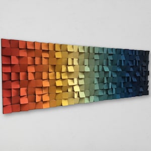 Op de afbeelding: Een wandkunstwerk gemaakt van houten vierkanten in een kleurverloop van rood naar blauw.