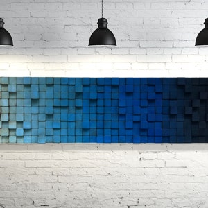 May include: A wall art piece made of wood blocks painted in shades of blue, transitioning from light to dark. The blocks are arranged in a grid pattern, creating a gradient effect.