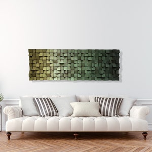 May include: A white sofa with striped pillows in front of a white wall with a green and brown geometric wall art piece.