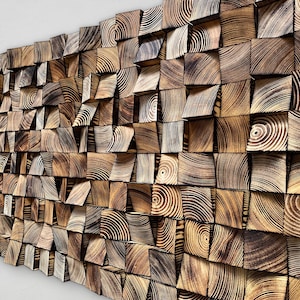Puede incluir: Una instalación de arte mural compuesta por numerosos bloques de madera. Los bloques son cuadrados y varían en profundidad, creando un efecto tridimensional texturizado. La veta de la madera es visible, con tonos marrones claros y oscuros.