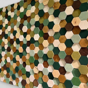 Könnte beinhalten: Ein Wandkunstwerk aus zahlreichen Holzsechsecken in verschiedenen Grün-, Braun- und Naturholztönen. Das geometrische Muster erzeugt einen strukturierten, dreidimensionalen Effekt und verleiht der Wanddekoration visuelles Interesse. Ein modernes, abstraktes Design.