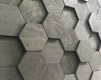 May include: A wall of gray wooden hexagonal tiles. The tiles are arranged in a honeycomb pattern, creating a textured, geometric design. The wood grain is visible, adding a natural element to the modern aesthetic.
