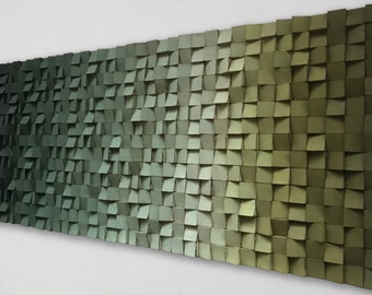 May include: A large, rectangular wall art piece composed of numerous small, square wooden blocks. The blocks are arranged in a gradient of greens and olive tones, creating a textured, three-dimensional effect. The artwork is mounted on a white wall.