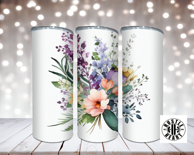 May include: Three white stainless steel tumblers with a floral design. The design features watercolor flowers in shades of pink, purple, blue, and yellow. The flowers are arranged in a bouquet with green leaves.