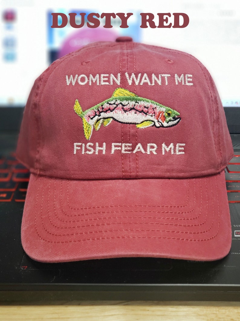 May include: Dusty red baseball cap with embroidered text "Women Want Me" and "Fish Fear Me" and a colorful fish graphic.