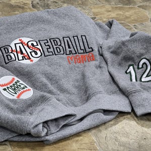 May include: Gray sweatshirt with the words "Baseball Mama" and a baseball graphic on the front. The left sleeve has a baseball graphic with the word "Torres" on it. The right sleeve has the number "12" on it.