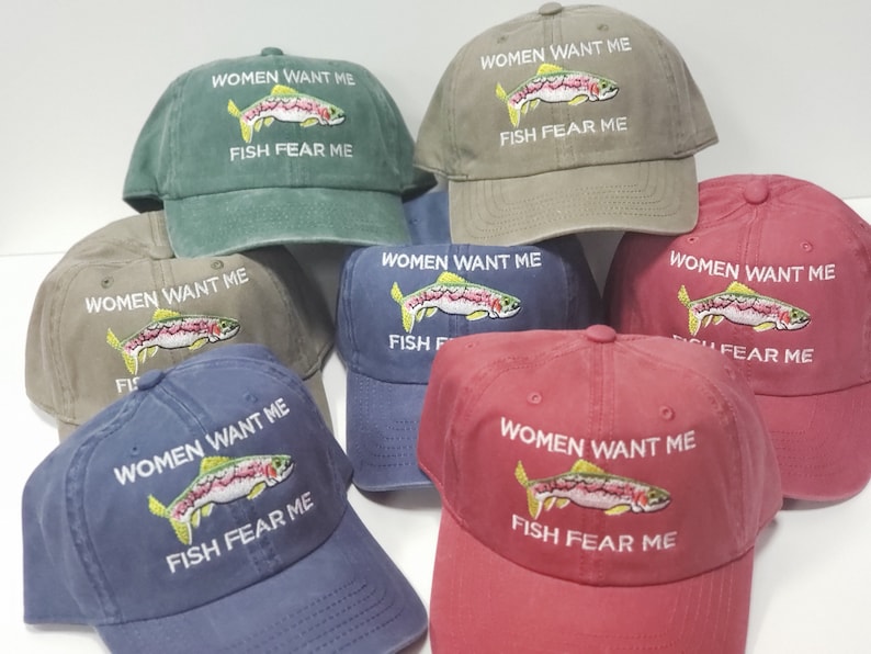 May include: Six different colored baseball caps with a rainbow trout embroidered on the front. The text "Women Want Me Fish Fear Me" is embroidered on each cap.