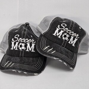 May include: Two black and gray trucker hats with white embroidered text that says "Soccer Mom" and a soccer ball graphic.