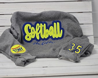 May include: Gray sweatshirt with yellow and blue embroidered text "Softball Mom" and a yellow and blue embroidered baseball with the text "Tony" on one sleeve and the number "35" on the other sleeve.
