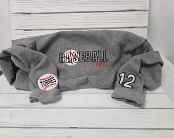 May include: Gray sweatshirt with the text "BASEBALL Mama" and a baseball graphic on the front. The left sleeve has a baseball graphic with the text "TORRES" and the right sleeve has the number "12" on it.