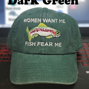 May include: Dark green baseball cap with white embroidery that reads "Women Want Me" and "Fish Fear Me". A rainbow trout is embroidered between the text.