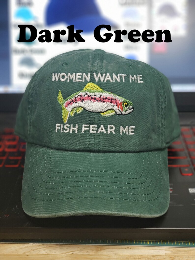 May include: Dark green baseball cap with white embroidery that reads "Women Want Me" and "Fish Fear Me". A rainbow trout is embroidered between the text.