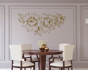 May include: A dining room with a round wooden table and four white chairs. The wall behind the table has a gold floral decal.