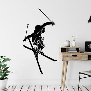May include: Black silhouette of a skier in mid-air, with skis and poles, against a white background.