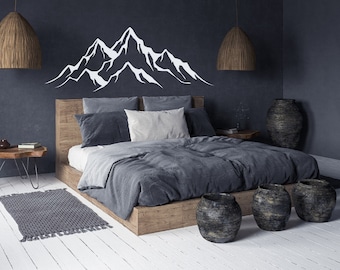 May include: A gray bed with a gray duvet cover and a white mountain range wall decal above the headboard. The bed is in a room with a dark gray wall and wooden floors. There are three black and brown ceramic pots on the floor in front of the bed.