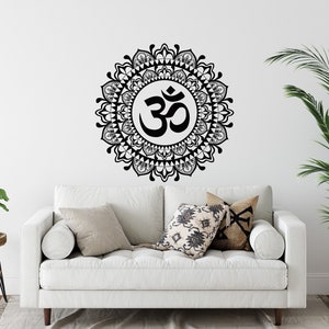 May include: A white couch with pillows in a living room setting. A black and white mandala wall decal with the symbol "Om" in the center is on the wall behind the couch.