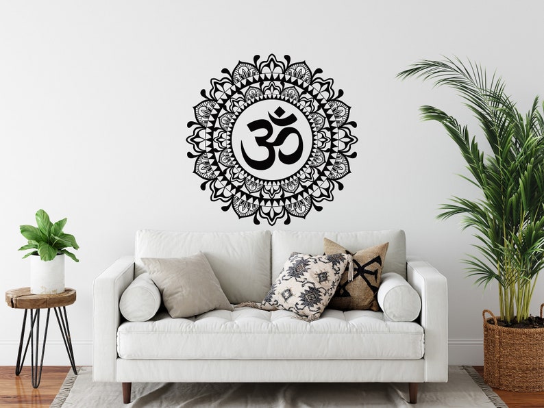 May include: A white couch with pillows in a living room setting. A black and white mandala wall decal with the symbol "Om" in the center is on the wall behind the couch.