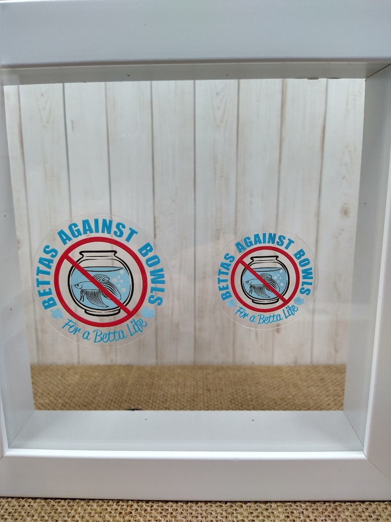 May include: Two white framed stickers with a red circle and a diagonal line through it. The stickers say "Betta's Against Bowls" and "For a Betta Life". The stickers feature a blue betta fish in a fishbowl.