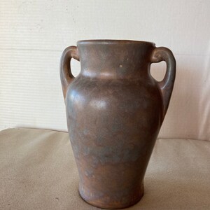 May include: A brown ceramic vase with two handles. The vase has a mottled glaze with a blue-grey hue.