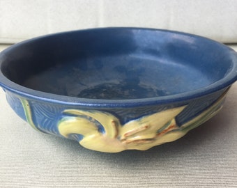 May include: A blue ceramic bowl with a yellow floral design. The bowl is round and has a slightly raised rim.