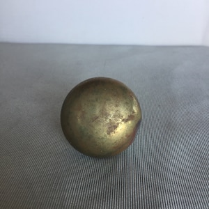 May include: A round, brass door knob with a worn, aged finish.