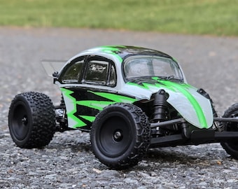 May include: A green and white toy car with black accents and a black windscreen. The car has a rounded body and large wheels.