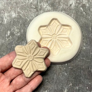 Peut inclure: Un moule à neige en céramique blanche et un flocon de neige en céramique assorti. Le moule est rond et présente un motif de flocon de neige en relief. Le flocon de neige est une pièce séparée et présente un design détaillé.