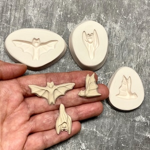 May include: Set of four silicone molds for making bat-shaped decorations. The molds are beige and feature different bat designs, including a bat with wings spread, a bat with wings folded, and a bat hanging upside down.