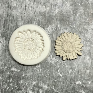 Peut inclure: Un moule en céramique blanche et un tournesol en céramique beige. Le moule est un motif en relief d'un tournesol.