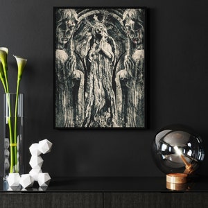 May include: A black and white framed print of a religious sculpture featuring a woman holding a child. The sculpture is flanked by two figures with their heads bowed. The print is hanging on a black wall with a vase of white calla lilies and a glass globe lamp on a wooden base.