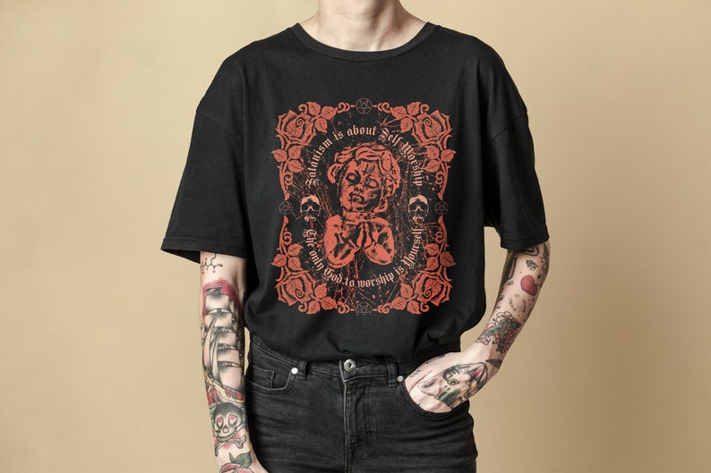 May include: Black t-shirt with a red graphic print of an angel with the text "Satanism is about Self Worship. The only God to worship is yourself."