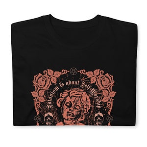 May include: Black t-shirt with a pink graphic design featuring a stylized image of a person's head with a pentagram on the forehead. The graphic also includes roses, skulls, and the text "Satanism is about Self Worship".