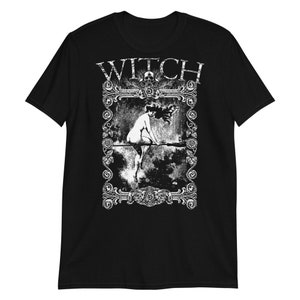 Peut inclure: T-shirt noir avec un graphique blanc d'une sorci&egrave;re chevauchant un balai dans un cadre d&eacute;coratif. Le texte "WITCH" est au-dessus de l'image.