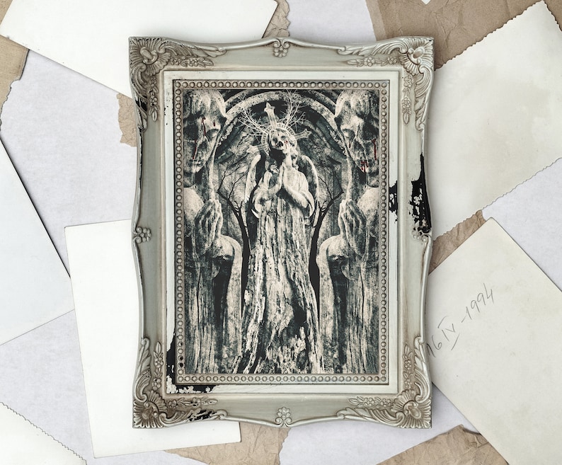 May include: A framed black and white print depicting a woman in a long dress standing in a forest, flanked by two figures. The figures are partially obscured by the trees and have a haunting, ethereal quality. The print is in a silver frame with ornate details.