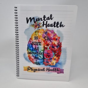 K&ouml;nnte beinhalten: Ein wei&szlig;es Spiralnotizbuch mit einer bunten Gehirnabbildung und dem Text "Mentale Gesundheit ist genauso wichtig wie k&ouml;rperliche Gesundheit".