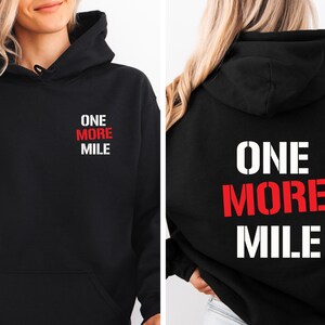 May include: Black hoodie with the text "ONE MORE MILE" in red and white on the front and back.