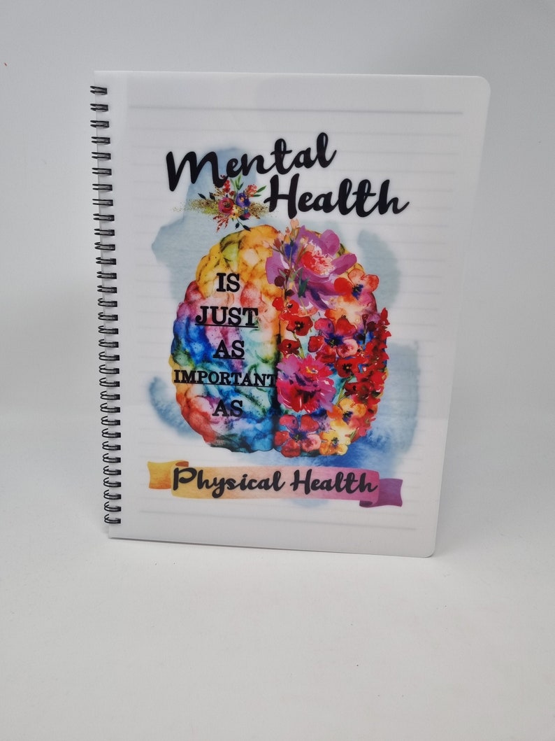 K&ouml;nnte beinhalten: Ein wei&szlig;es Spiralnotizbuch mit einer bunten Gehirnabbildung und dem Text "Mentale Gesundheit ist genauso wichtig wie k&ouml;rperliche Gesundheit".
