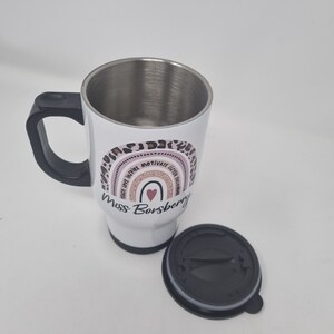 May include: White stainless steel travel mug with a black handle and lid. The mug has a pink and brown rainbow design with the text "Teach Love Inspire Motivate  Little Humans" and "Miss Borsberry".