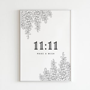 Puede incluir: Impresión en blanco y negro con los números 11:11 y el texto "Make a Wish" rodeado de diseños florales.