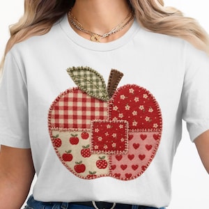 May include: A white short-sleeved t-shirt featuring a large, central apple-shaped graphic. The apple is composed of various fabric-like patches in red, white, and green, displaying patterns of gingham, small flowers, hearts, and tiny apples with visible stitching.