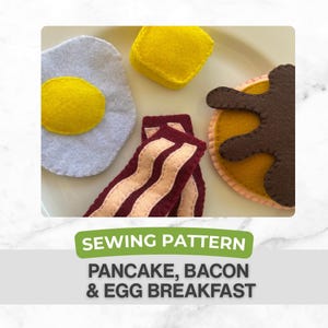 May include: A felt breakfast set including a fried egg, butter, bacon strips, and a pancake. The egg has a yellow yolk and a gray white. The bacon is red with beige stripes. The pancake is brown with a yellow base. The text reads "SEWING PATTERN PANCAKE, BACON & EGG BREAKFAST."
