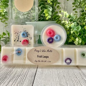 May include: A white wax melt snap bar with a label that reads "Penny's Wax Melts Fruit Loops Snap Bar Net Wt. 3.2oz". The bar is divided into six squares, each with a different design of colorful fruit loops.