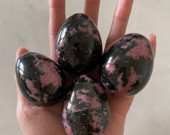 May include: Four polished, egg-shaped stones with a black and pink marbled pattern.