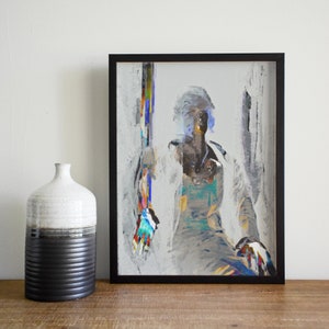 May include: Abstract art print in a black frame. The artwork features a figure with a white coat and colorful accents. A ceramic vase with a black and white design sits to the left of the framed art.