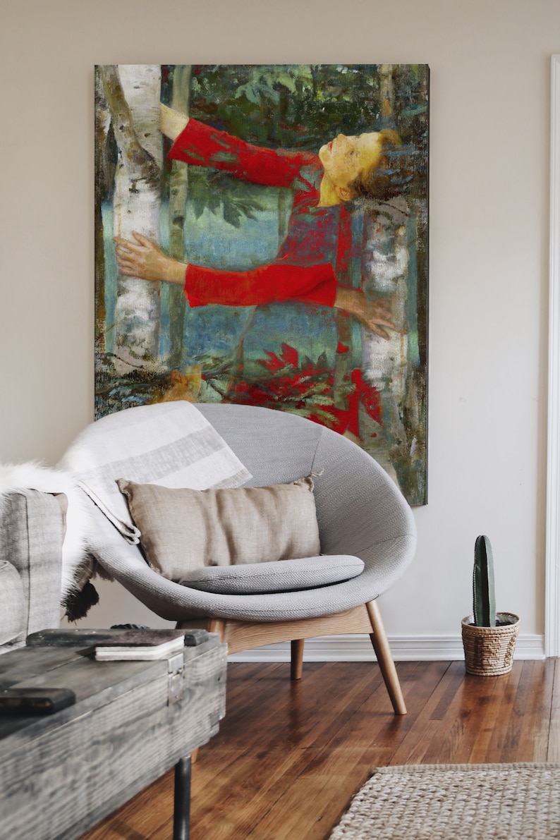 K&ouml;nnte beinhalten: Ein gro&szlig;er Leinwanddruck eines Gem&auml;ldes, das eine Person in einem roten Kleid zeigt, die einen Baum in einem Wald umarmt. Das Kunstwerk h&auml;ngt &uuml;ber einem grauen Stuhl mit einem beigen Kissen. Ein Holztisch und ein Kaktus in einem geflochtenen Topf sind ebenfalls zu sehen.